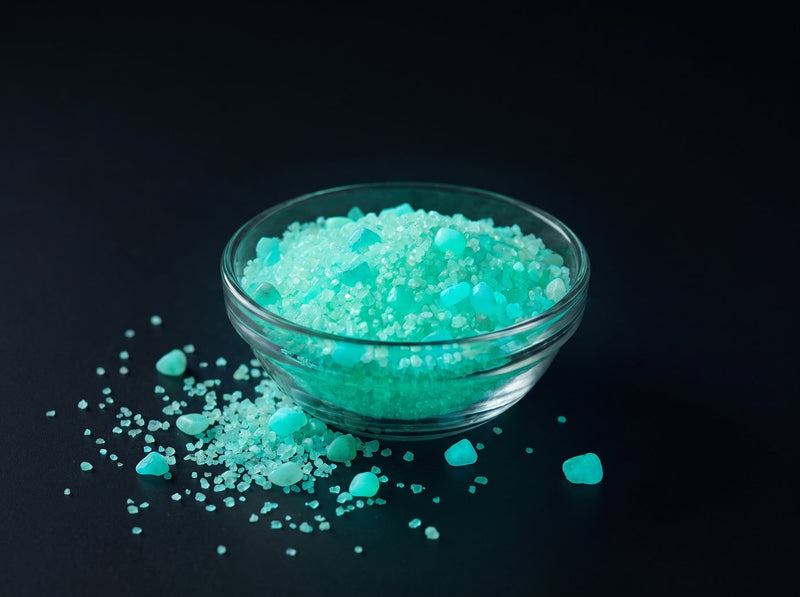 Leuchtgranulat Grün 1 mm, 100 g in einer Glasschale, im Dunkeln grün leuchtend