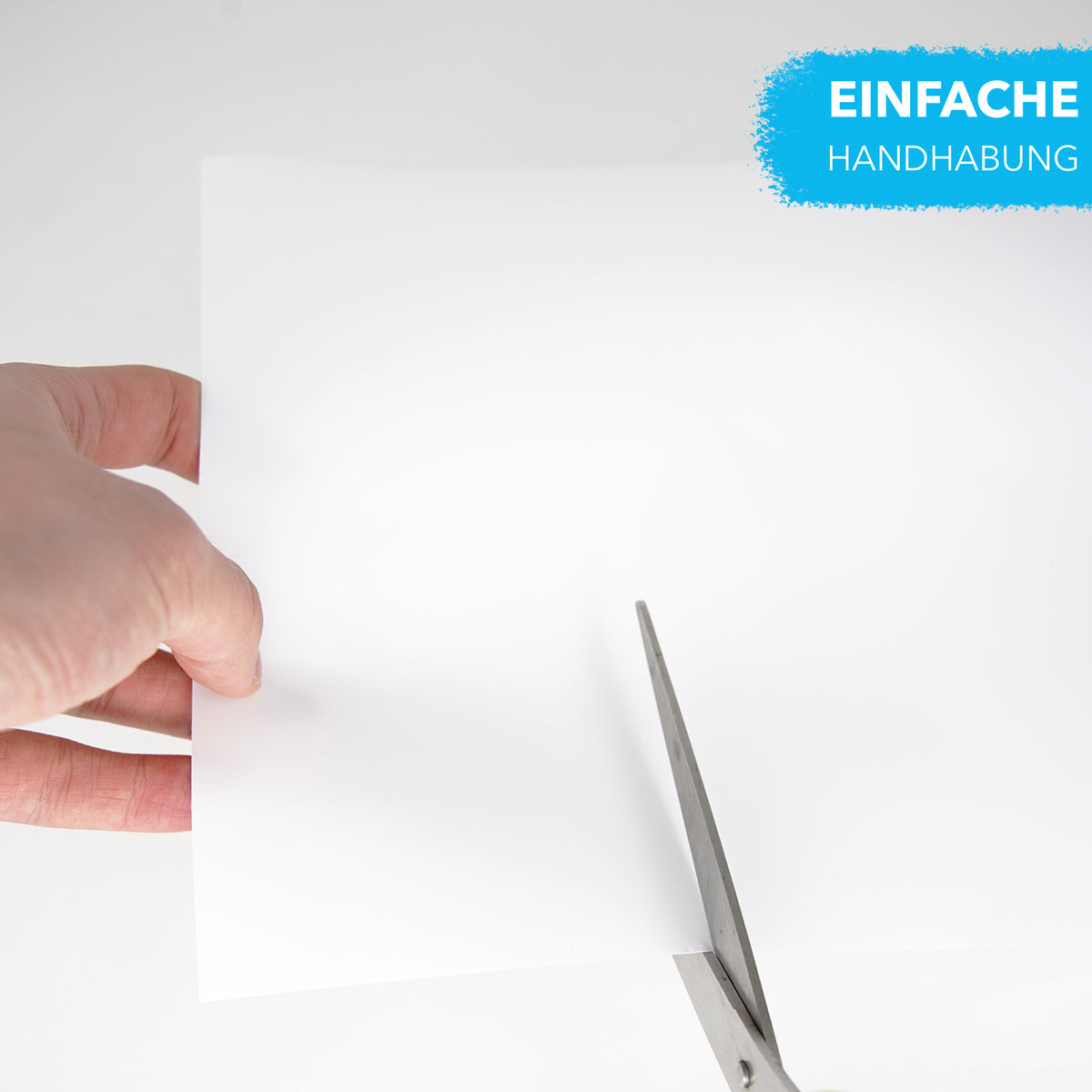 Leuchtpapier wird mit einer Schere geschnitten, Hand hält den weißen Bogen