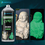 Leuchtspray Silber-Grün 400 ml neben einer Buddha-Figur, bei Tageslicht silbrig weiß, im Dunkeln grün leuchtend