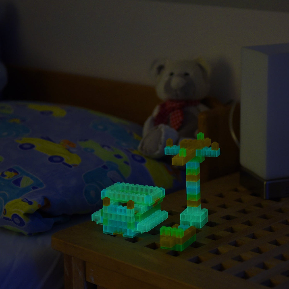 Aus Klemmbausteinen gebaute Modelle auf einem Nachttisch, im Dunkeln grünlich leuchtend