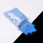 Feinpigment Blau-Blau 100 g: aufgeschnittener Beutel und Häufchen feines Pulver, bei Tag blau, rechts unten im Dunkeln blau leuchtend