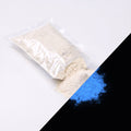 Feinpigment Natur-Blau 100 g: aufgeschnittener Beutel und Häufchen feines Pulver, bei Tag weißlich, rechts unten im Dunkeln blau leuchtend