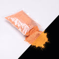 Feinpigment Orange-Orange 100 g: aufgeschnittener Beutel und Häufchen feines Pulver, bei Tag orange, rechts unten im Dunkeln orange leuchtend