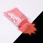 Feinpigment Rot-Rot 100 g: aufgeschnittener Beutel und Häufchen feines Pulver, bei Tag hellrot, rechts unten im Dunkeln rötlich leuchtend