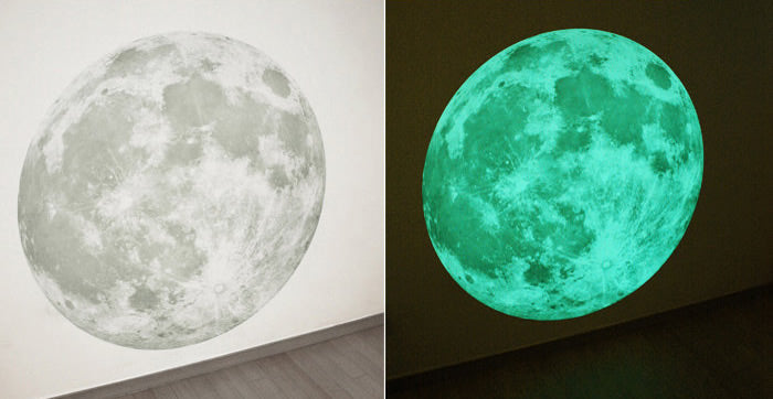 Mond-Aufkleber an einer Wand, links bei Tageslicht in Grau, rechts im Dunkeln leuchtend