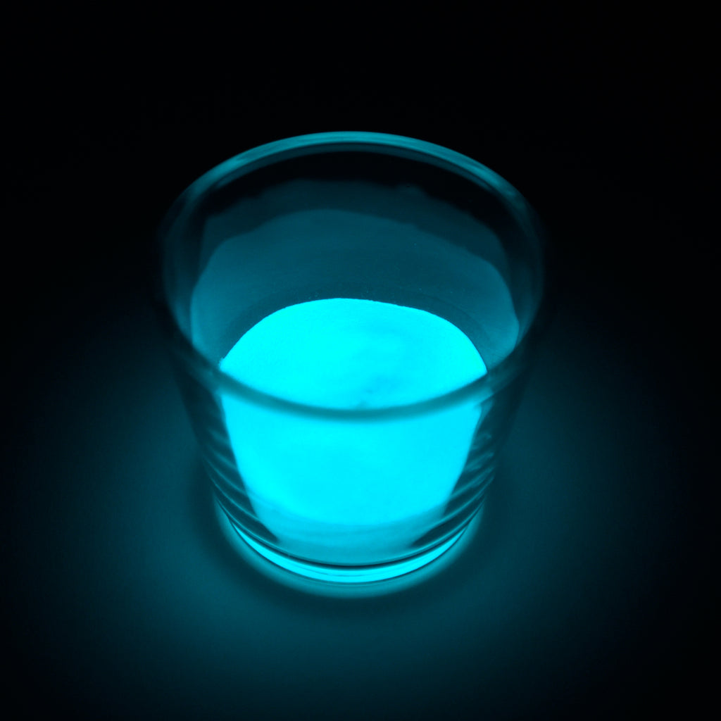 Leuchtgranulat Blau 1 mm in einem Glas im Dunkeln, blaugrün leuchtend