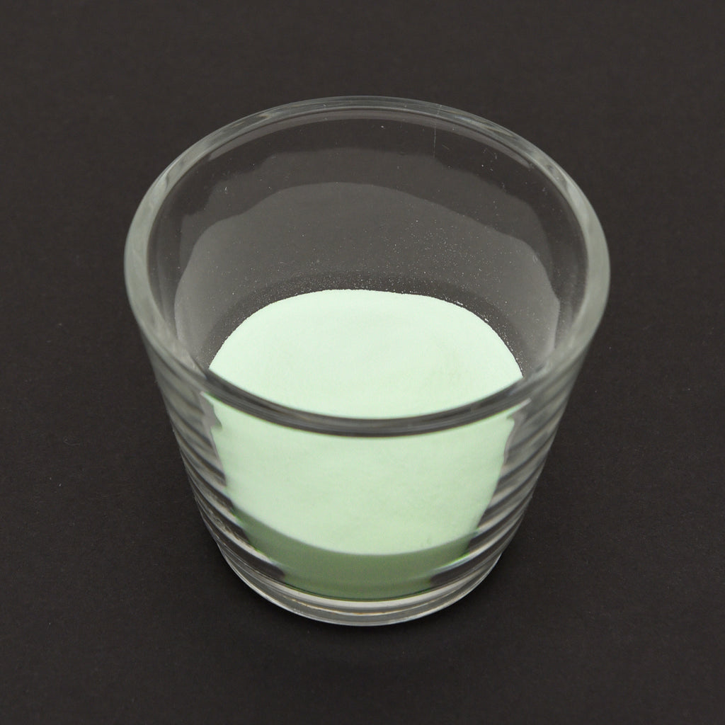 Leuchtgranulat Blau 1 mm in einem Glas bei Tageslicht, blassgrün