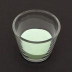 Leuchtgranulat Blau 1 mm in einem Glas bei Tageslicht, blassgrün