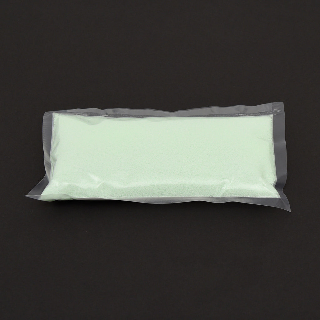 Leuchtgranulat Blau 1 mm im durchsichtigen Beutel, blassgrünes Granulat auf dunklem Grund