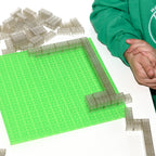 Kinderhand setzt transparente Klemmbausteine 2x4 zu einem Rahmen zusammen